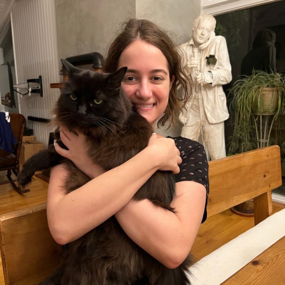 Lyndsay smiling while holding a fluffy black cat